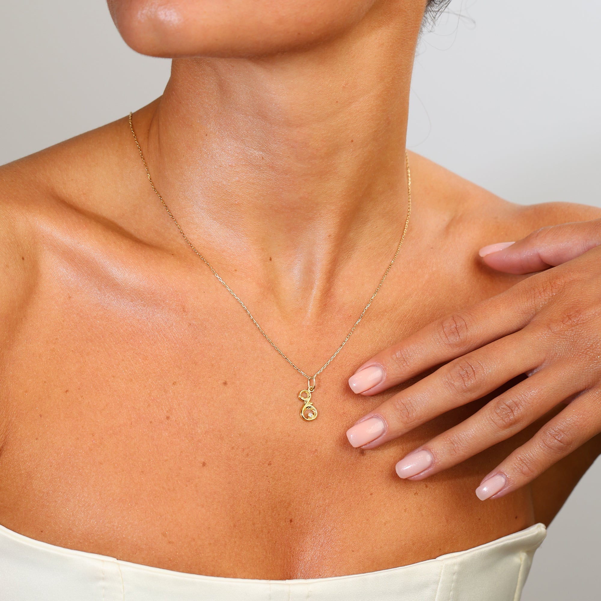 Necklace with a pendant worn by a person, with a hand touching the neck.