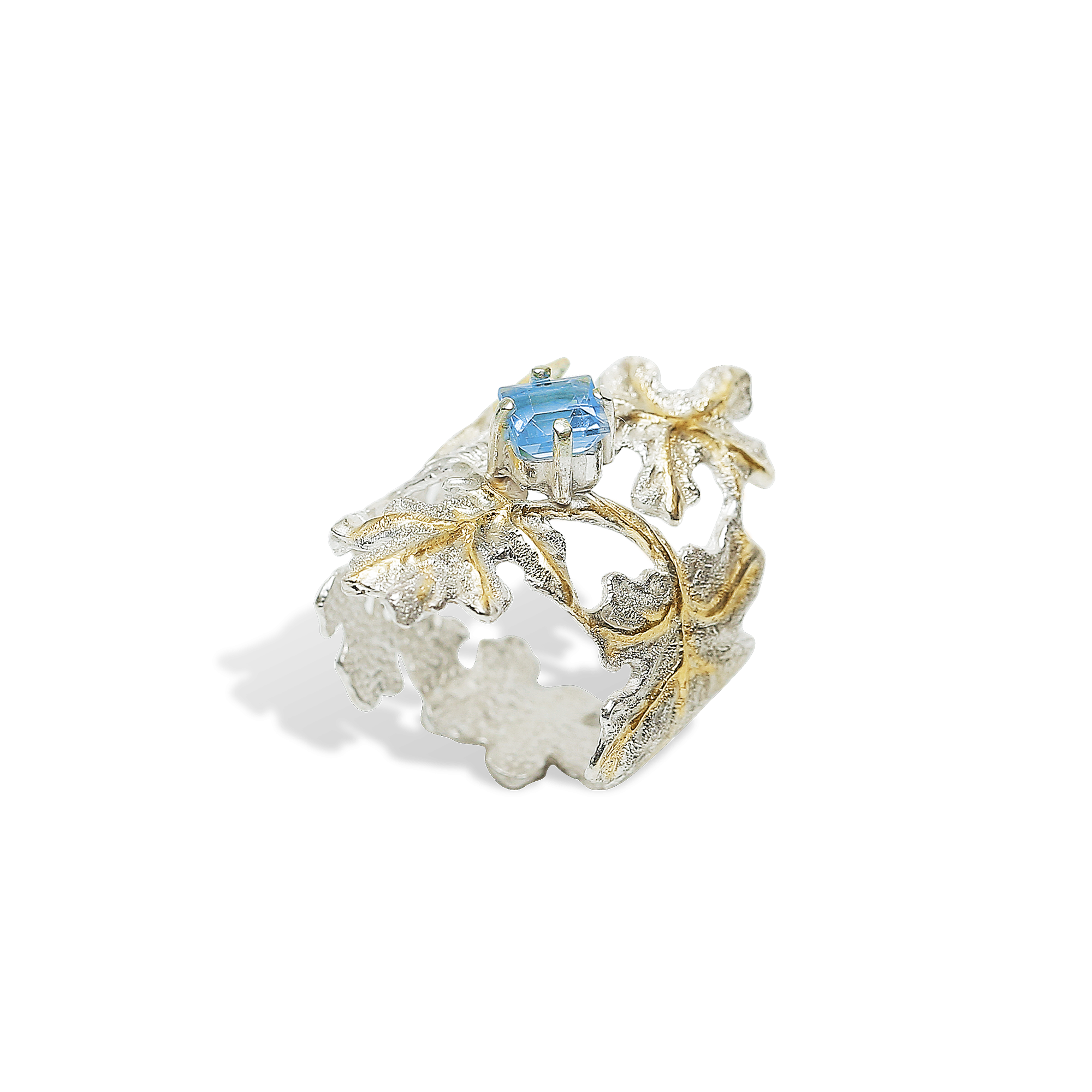 Gold and silver ring with a blue gemstone on a white background