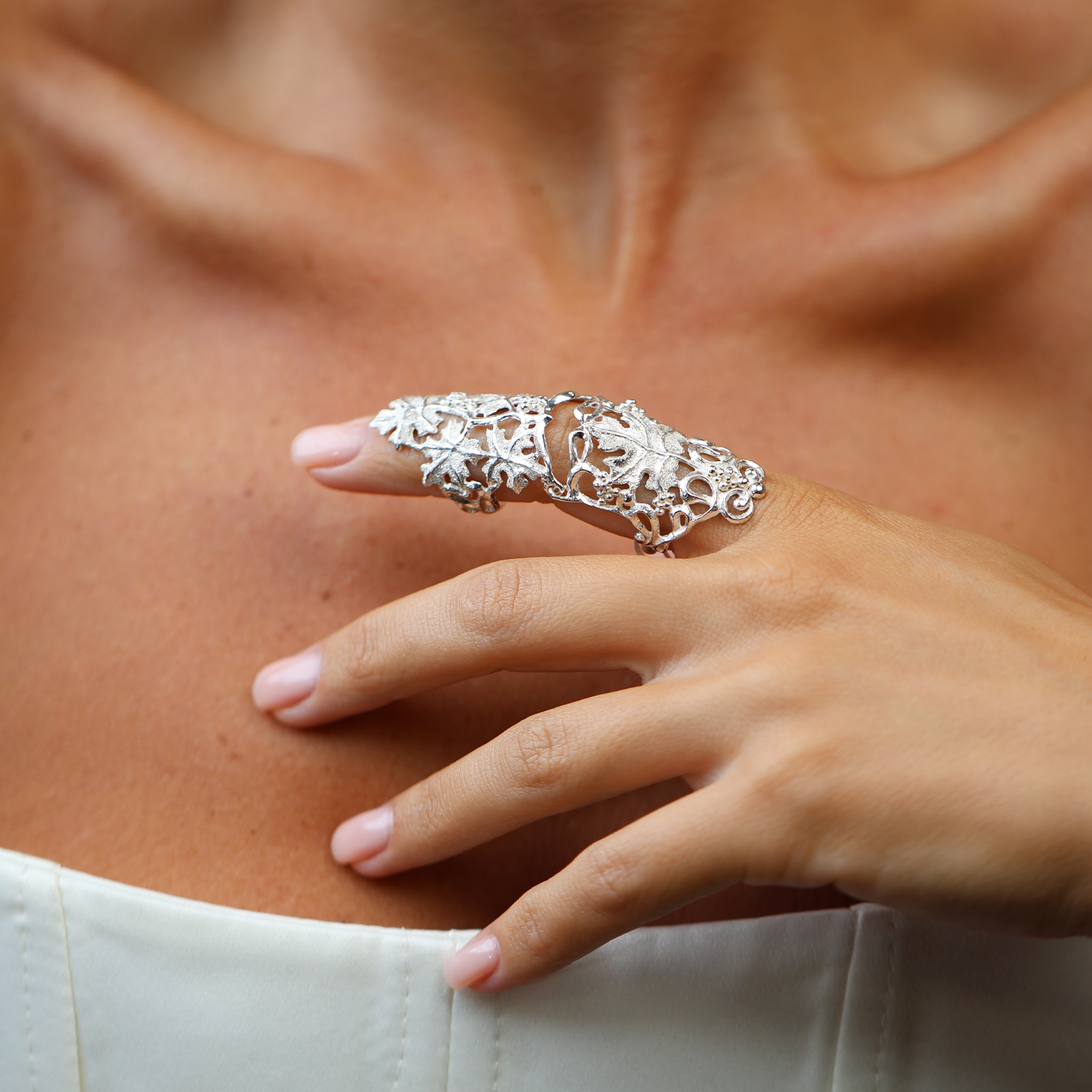 Silver armor ring on a person's finger against a neutral background