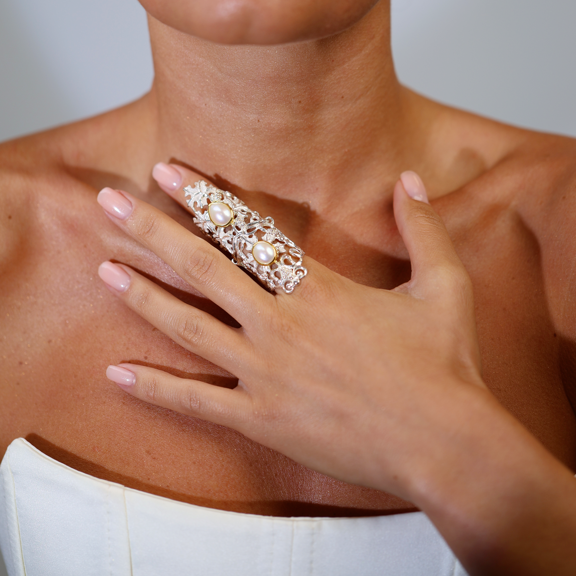 Close-up of a hand wearing a decorative ring on a blurred background